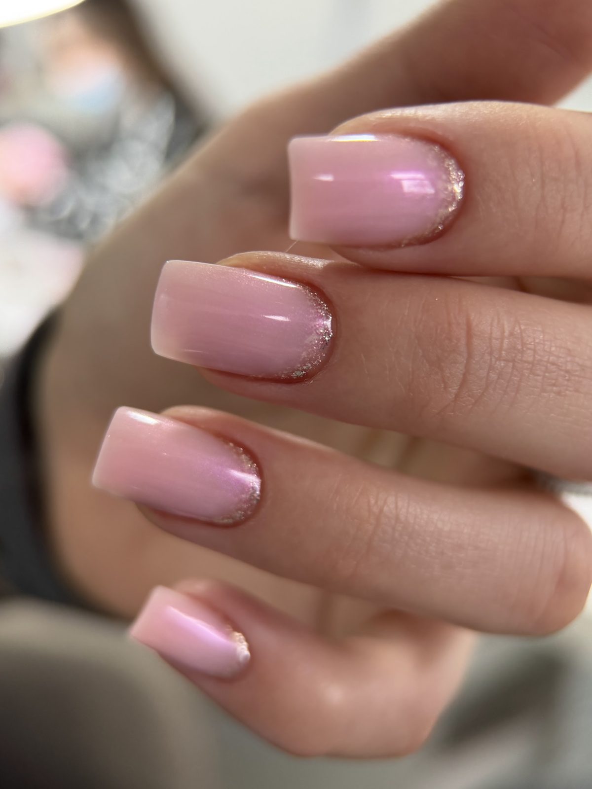 Roze gellak met een fijne gouden glitterrand bij de nagelriem